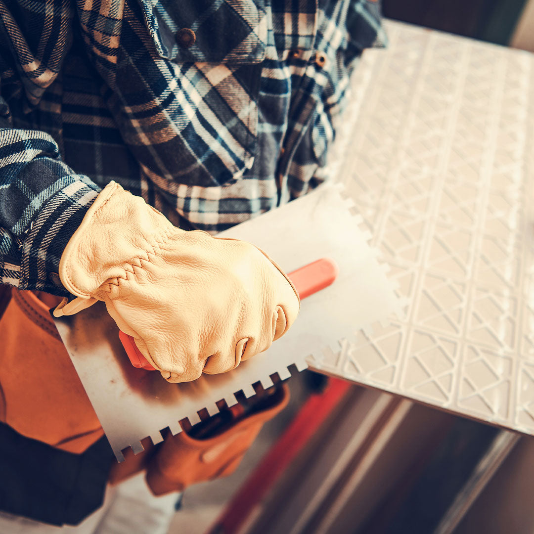 Tile adhesive being troweled on porcelain tile