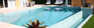 Swimming pool with a light green glass tile pool finish